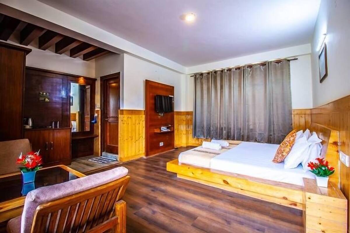 A wooden-floored room with a bed, a desk, and a chair.