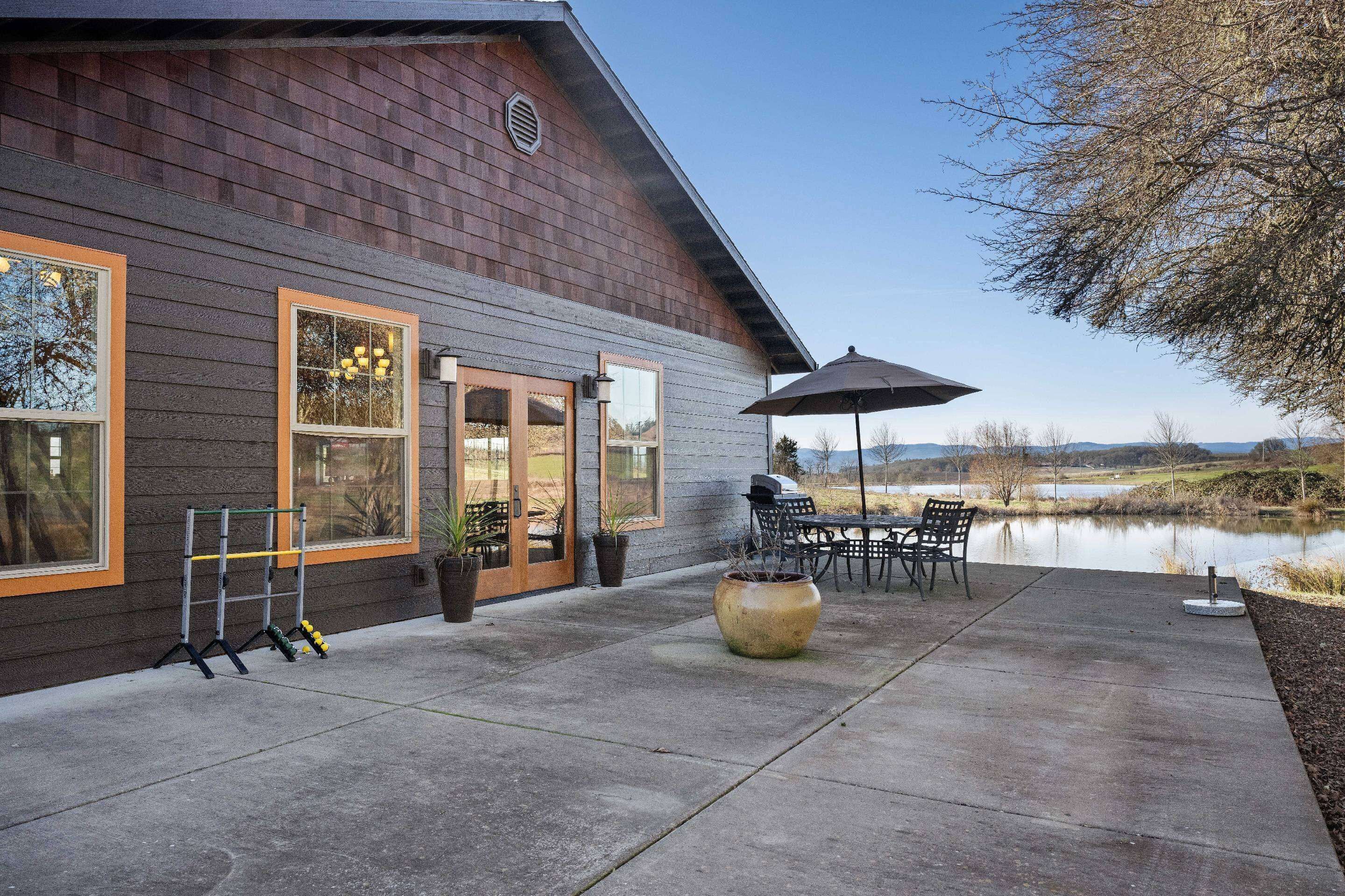 A house with a patio area featuring outdoor furniture, a grill, and a view of a lake.