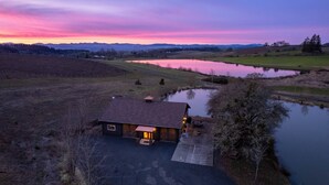 Un chalet rustique doté d’une grande véranda, d’un étang et offrant une vue magnifique sur le coucher de soleil.