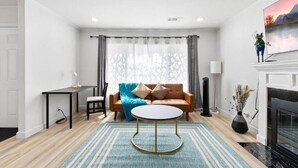 A modern living room with a brown leather sofa, a round coffee table, and a fireplace. - Bright & Peace 3BR, RWC Fresh Remodeled & Spotless (Redwood City)