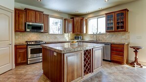 A kitchen with wooden cabinets, granite countertops, a central island, stainless steel appliances, and a window providing natural light. - Fantastic Eagle Crest Home, Resort Pool, Fitness Center, Golf, Pickleball, Fireplace, Quiet Street (Redmond)