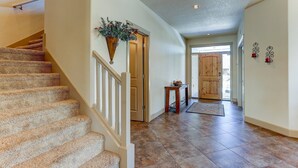 A staircase leading to a door, a small table with a vase, and a rug on a tiled floor. - Fantastic Eagle Crest Home, Resort Pool, Fitness Center, Golf, Pickleball, Fireplace, Quiet Street (Redmond)