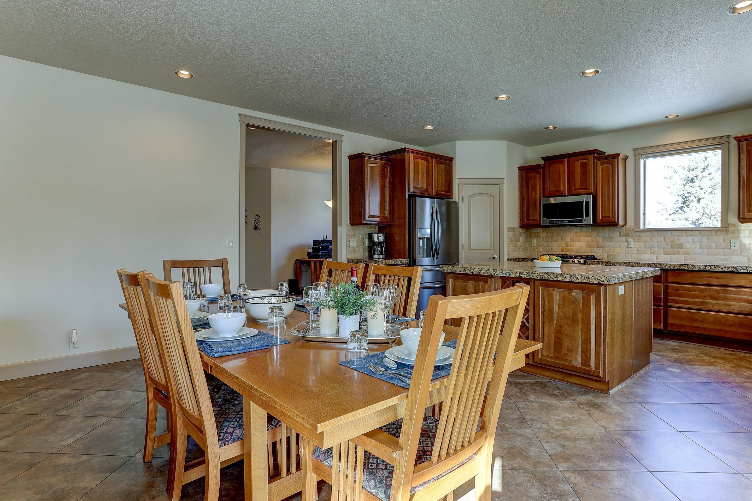 A spacious kitchen with wooden cabinets, a central island, and a dining area with a wooden table and chairs.