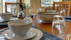 A dining table set with white bowls, plates, and glasses, along with a bottle of wine and a salt shaker. - Fantastic Eagle Crest Home, Resort Pool, Fitness Center, Golf, Pickleball, Fireplace, Quiet Street (Redmond)