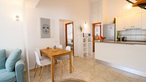A compact living space with a dining area, a kitchenette, and a bedroom visible through an open door. - Nice Bungalow next to Denia (Denia)