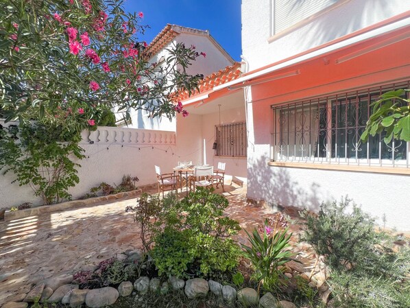 A patio area with a table and chairs, surrounded by plants and a stone pathway. - Nice Bungalow next to Denia (Denia)