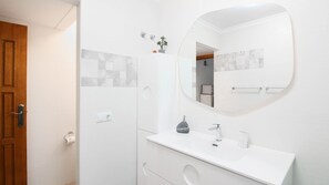 A modern bathroom with a white vanity, a round mirror, and a small potted plant on the wall. - Nice Bungalow next to Denia (Denia)