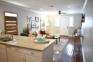 A modern kitchen with granite countertops, a built-in sink, and a dining area with a coffee table and chairs. - Eclectic West Riverside Apt | 6 min to Audobon Zoo (New Orleans)