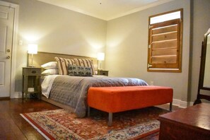 A bedroom with a bed, two bedside tables, a nightstand, a bench, a window with blinds, and a rug. - Eclectic West Riverside Apt | 6 min to Audobon Zoo (New Orleans)
