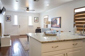 A modern kitchen with a marble countertop, a built-in sink, and a ceiling fan.
