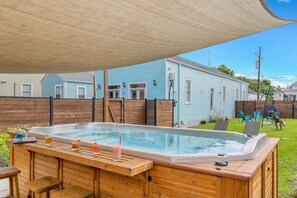 A backyard with a hot tub, wooden deck, and a covered patio area. - Private Luxury Home w/ Swim Spa, Walk to FR QTR (New Orleans)