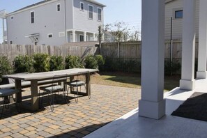 A patio with a table and chairs, a wooden fence, and a house in the background.
