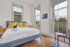 A bedroom with a bed, two nightstands, a chair, and large windows. - Family Perfect Point Home |  Luxury at its Best (New Orleans)