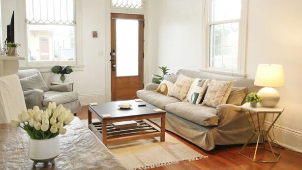 A living room with a sofa, coffee table, and a lamp. - West Riverside Shotgun Near Audubon Park (New Orleans)