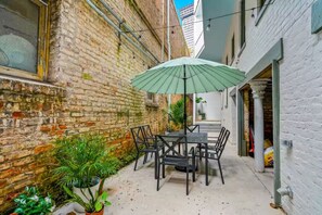 A patio with a table and chairs, surrounded by brick walls and potted plants.