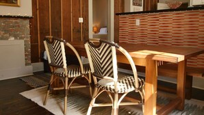 A dining area with a wooden table and two wicker chairs.