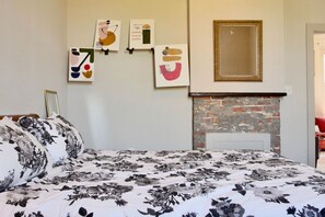 Une chambre à coucher avec un lit, une cheminée et des œuvres d’art abstrait accrochées au mur.