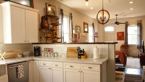 A kitchen with white cabinets, a wooden countertop, and various kitchen items.