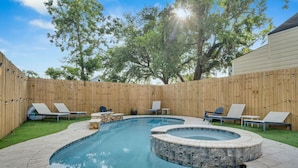 Ein Garten mit Swimmingpool, Whirlpool und Liegestühlen.