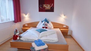 A neatly made bed with pillows and folded towels, a small stool with towels, a plush toy, and a wall art piece. - Retreat in Samnaun Alps (Samnaun)