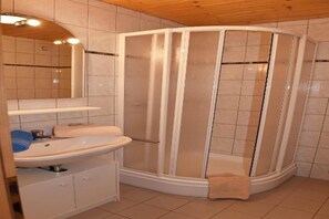 Une salle de bain avec une douche, un lavabo et un miroir.