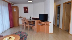 A compact hotel room with a desk, television, and a small seating area. - Retreat in Samnaun Alps (Samnaun)