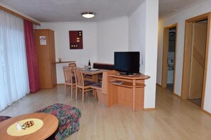 A compact hotel room with a desk, television, and a small seating area.