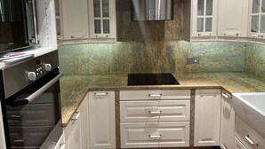 Una cocina moderna con armarios blancos, una campana extractora de acero inoxidable y una encimera de granito.