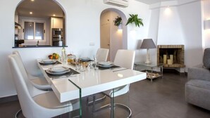 A modern living room with a dining area, white furniture, a chandelier, and a fireplace. - Deltamar by Interhome (Jávea)