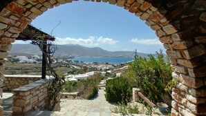 A stone pathway leading to a view of a coastal town with white buildings, a clear sky, and mountains in the distance. - Parian Beach House with Pool Access, walk to the Beach (Paros)