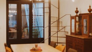 Un espace repas comprenant une table, des chaises, un lustre et un escalier.