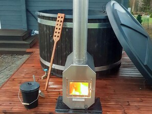 A wood-burning stove with a visible fire, a metal chimney, and a wooden spoon. - Adeli holiday cottage ellivuori by Interhome (Sastamala)