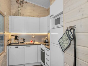 A modern kitchen with white cabinetry, a built-in microwave, and a kettle on the counter. - Adeli holiday cottage ellivuori by Interhome (Sastamala)