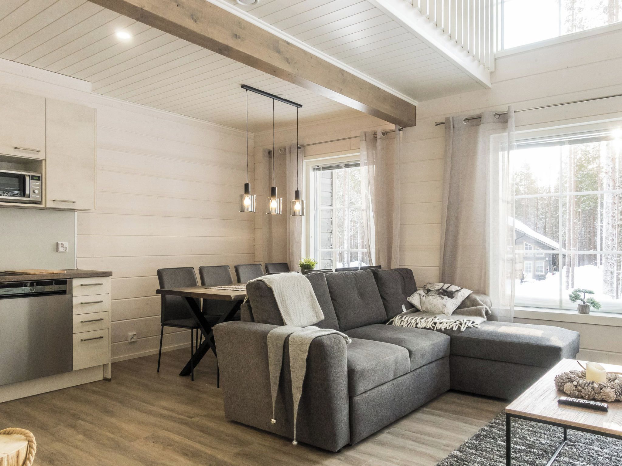 A modern kitchen with a built-in microwave, a dining area with a table and chairs, and a cozy seating area with a sofa and a coffee table.