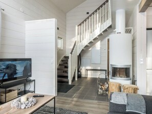 Una sala de estar moderna con chimenea, televisión y una escalera que sube a otro nivel.