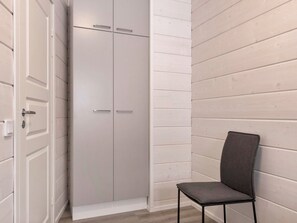 Een kamer met een kledingkast, een stoel en houten paneelwanden.