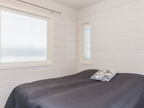 Une pièce avec un lit, deux fenêtres et un ventilateur de plafond.