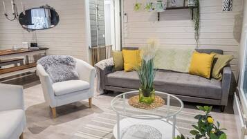 Una sala de estar moderna con un sofá, un sillón y una mesa de centro de vidrio.