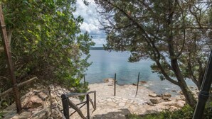 A stone staircase leading to a beach with clear water and a distant view of land. - La Nina by Interhome (Porto Rotondo)