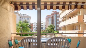 Ein Balkon mit Tisch und Stühlen, mit Blick auf ein Wohngebiet mit Gebäuden und Grünflächen.