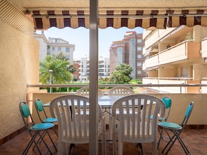 Un balcon avec une table et des chaises, donnant sur un quartier résidentiel avec des immeubles et de la verdure.