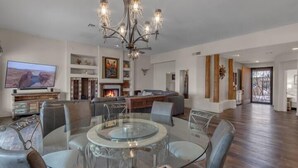 Amplia sala de estar con una mesa de centro de vidrio, asientos cómodos, chimenea y un televisor de pantalla plana grande.