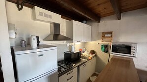Cocina compacta con refrigerador, estufa, microondas y horno.