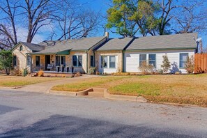 A two-story house with a front porch, a garage, and a well-maintained lawn. - Ruth's Place - Walk to Main, Hot Tub & Fire Pit (Fredericksburg)