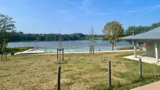 Een grasveld met een kiosk en uitzicht op een meer.