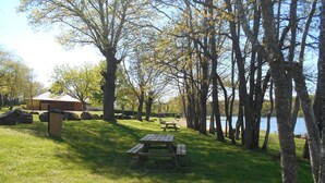Een picknickplaats met banken en een prullenbak, omgeven door bomen en een meer.
