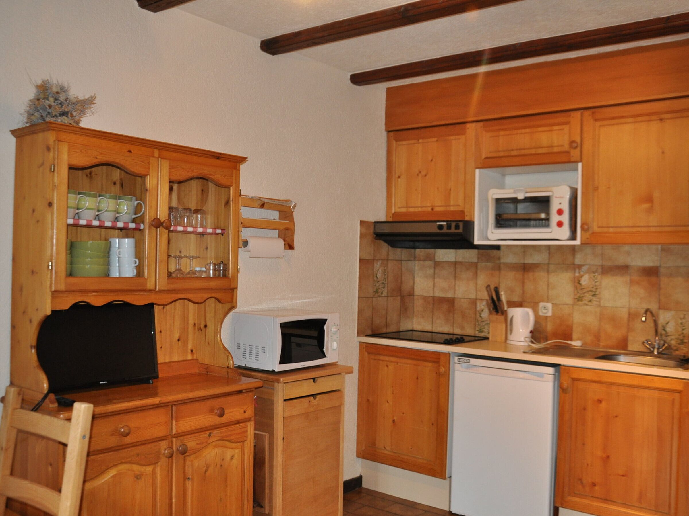 Une cuisine compacte avec des meubles en bois, un four à micro-ondes, un lave-vaisselle et un petit plan de travail.