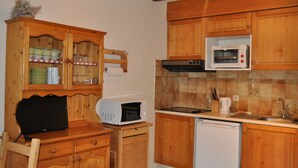 Une cuisine compacte avec des meubles en bois, un four à micro-ondes, un lave-vaisselle et un petit plan de travail.