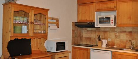Une cuisine compacte avec des meubles en bois, un four à micro-ondes, un lave-vaisselle et un petit plan de travail.