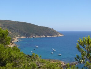 Un paisaje costero con vista despejada al mar, barcos y un terreno montañoso.